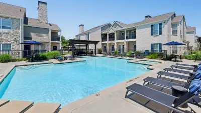 Inviting apartment community with a swimming pool, elegant architecture, and relaxing lounge chairs, perfect for luxurious living.