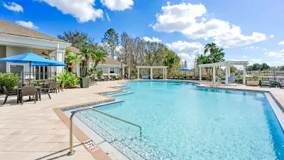 Luxurious poolside view of a serene residential complex with stylish patio seating and lush landscaping, perfect for relaxation and entertainment.