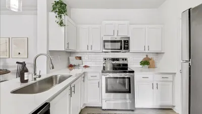 Chic modern kitchen featuring sleek white cabinetry, stainless steel appliances, and elegant countertop finishes.