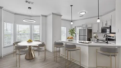 Contemporary open-concept kitchen and dining area with sleek appliances, chic pendant lighting, and a stylish round dining table by large, bright windows.