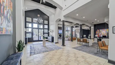 Elegant apartment lobby with high ceilings, stylish chandeliers, modern furniture, and vibrant artwork creating a welcoming and luxurious atmosphere.