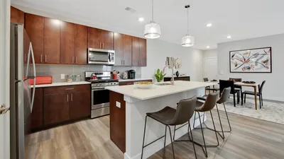 Modern kitchen with sleek cabinets, stainless steel appliances, and a spacious island, seamlessly connected to an elegant dining area with stylish art decor.