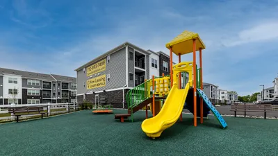 Modern apartment complex with vibrant playground, showcasing family-friendly living and luxury rentals.