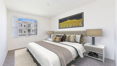 Bright and inviting bedroom with a plush bed, modern decor, and a large window offering scenic views.