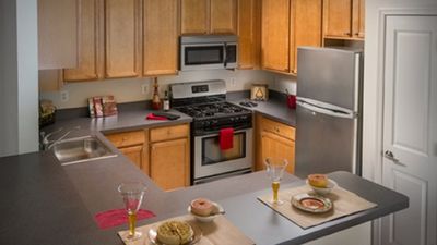 Modern kitchen with elegant wooden cabinets, sleek countertops, stainless steel appliances, and a cozy breakfast nook set for dining.