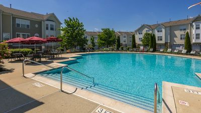 Inviting apartment complex with a sparkling outdoor pool, surrounded by lush greenery and comfortable seating areas.