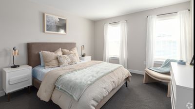 Chic bedroom with plush bedding, modern nightstands, and soft natural light through large windows.