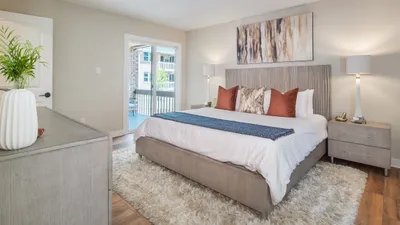 Luxurious bedroom featuring a plush king-sized bed with stylish cushions, elegant bedside lamps, and a serene balcony view.