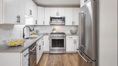 Modern kitchen showcasing sleek white cabinetry, stainless steel appliances, and elegant wood flooring.