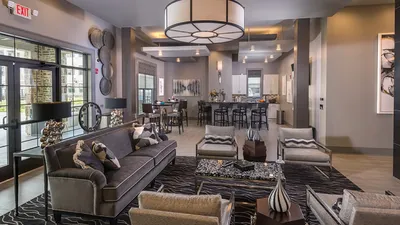 Chic and modern open-concept living area with stylish seating, elegant lighting, and a contemporary kitchen, creating a warm and inviting atmosphere.
