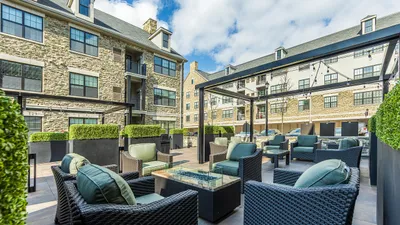 Chic outdoor courtyard with stylish wicker seating and lush greenery at a modern apartment complex.