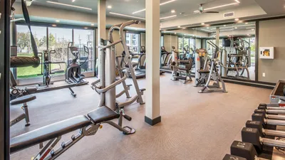 Modern fitness center with state-of-the-art exercise equipment, mirrored walls, and ample natural light.