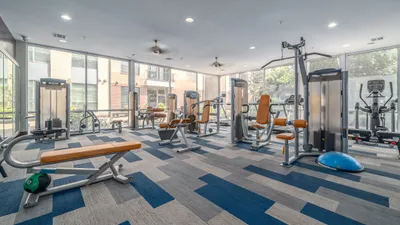 Bright and modern fitness center featuring state-of-the-art exercise equipment, expansive windows, and stylish flooring.