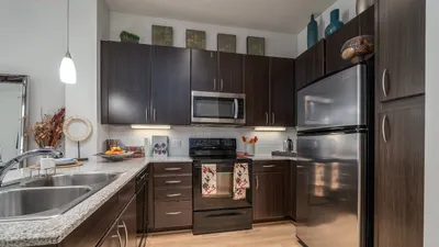 Elegant contemporary kitchen featuring dark wood cabinetry, stainless steel appliances, and cozy ambient lighting.