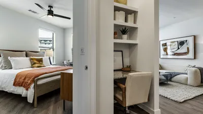 Elegant modern apartment showcasing a cozy bedroom, stylish home office nook, and open living room with artistic decor.