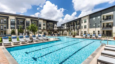 Luxurious apartment complex featuring a sparkling resort-style pool with modern lounge chairs and beautifully landscaped surroundings.