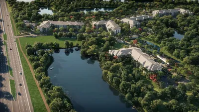 Scenic aerial view of luxurious lakeside apartment community surrounded by lush greenery and serene water features.