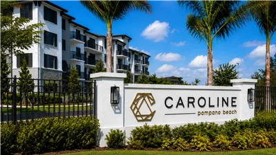 Chic apartment complex at Caroline Pompano Beach with elegant architecture, lush greenery, and a welcoming atmosphere under clear blue skies.
