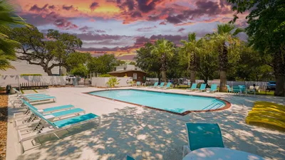 Inviting outdoor pool area surrounded by palm trees with vibrant sunset sky, perfect for relaxation and leisure.