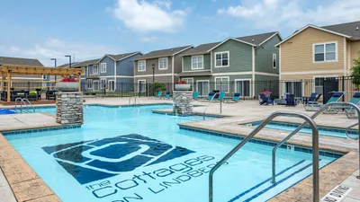 Inviting swimming pool area at The Cottages on Lindberg, surrounded by modern townhouses and cozy outdoor seating with a pergola, perfect for relaxation and leisure.