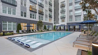 Luxurious apartment complex courtyard featuring a sparkling pool, stylish lounge chairs, and elegant cabanas, perfect for relaxation and social gatherings.