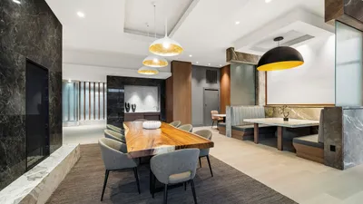 Elegant modern dining area with a luxurious wooden table, comfortable upholstered chairs, and chic pendant lighting creating a warm ambiance.