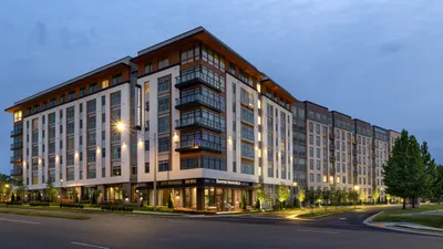 Elegant apartment complex bathed in warm evening light, showcasing modern architectural design with sleek balconies and lush landscaping.
