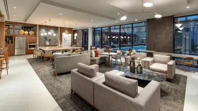 Luxurious, modern open-plan living area with elegant furnishings, stylish lighting, and large windows overlooking a serene pool.