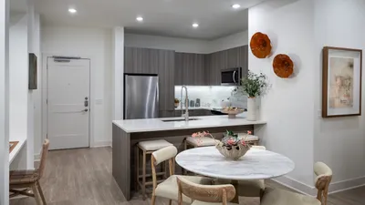 Elegant modern kitchen with stainless steel appliances, stylish wood cabinetry, and a cozy dining area with a marble table.