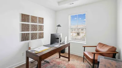 Bright home office with modern decor, featuring a sleek desk, comfortable seating, and a large window with an uplifting outdoor view.