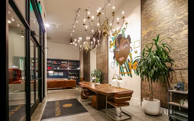 Chic lobby area featuring an elegant chandelier, artistic mural, and modern wooden furnishings.