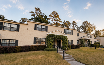 Charming townhouse complex with well-maintained lawns, classic brick exteriors, and lush greenery, perfect for serene living.