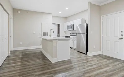 Modern kitchen with sleek stainless steel appliances, elegant white cabinetry, and a spacious island, all set on beautiful hardwood flooring.