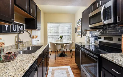 Chic modern kitchen with elegant dark cabinets, granite countertops, and a cozy breakfast nook bathed in natural light.