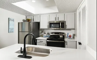 Modern kitchen with sleek white cabinetry, stainless steel appliances, and elegant black fixtures. Bright and inviting space perfect for culinary adventures.