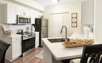 Contemporary kitchen with sleek white cabinets, stainless steel appliances, and stylish wooden accents offering a modern cooking space.