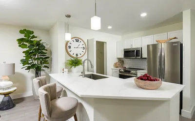 Modern kitchen with sleek marble countertop, stainless steel appliances, stylish barstools, and elegant decor for a sophisticated living space.
