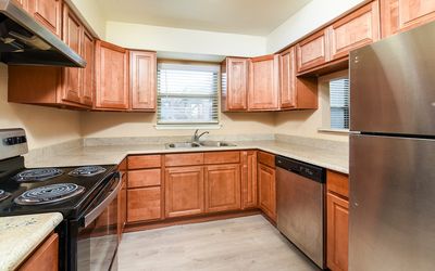 Charming kitchen with elegant wooden cabinetry, stainless steel appliances, and a bright, airy atmosphere enhanced by large windows.