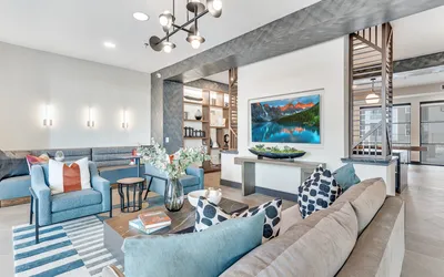 Modern clubhouse with stylish furnishings, vibrant decor, and a large scenic wall art enhancing a cozy atmosphere.