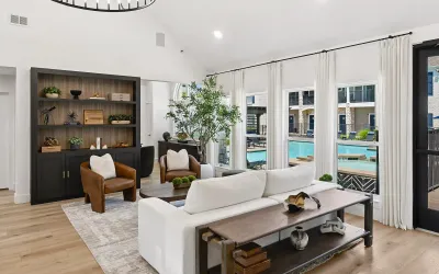 Leasing office with 2 chairs, a coffee table, a sofa, two ottomans all next to windows overlooking the pool area.