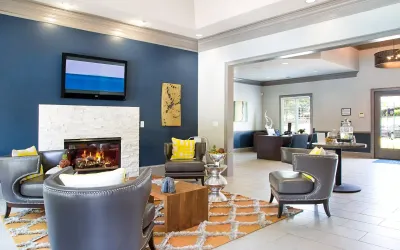 Modern and inviting clubhouse lounge with sleek gray seating, stylish decor, and a cozy fireplace for an elegant living experience.