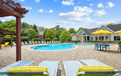 Inviting swimming pool area with modern lounge chairs, vibrant umbrellas, and a scenic backdrop, perfect for relaxation.