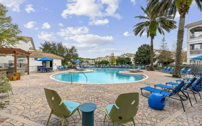 Luxurious apartment community with a stunning pool, elegant lounge chairs, and a modern outdoor seating area under a stylish pergola.