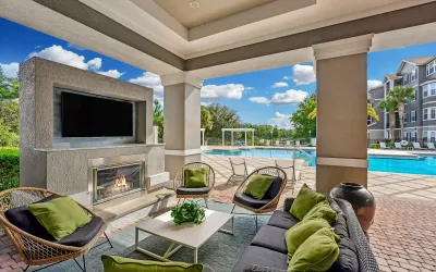 Luxurious outdoor lounge area with comfortable seating, a cozy fireplace, and a stunning pool view, perfect for relaxation and entertainment.