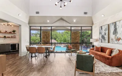 Modern clubhouse interior featuring a stylish living area with vibrant decor, large windows offering a stunning pool view, and an elegant dining space.