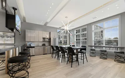 Chic modern kitchen and dining area with sleek cabinetry, stylish bar stools, and elegant lighting, offering a bright and inviting atmosphere.