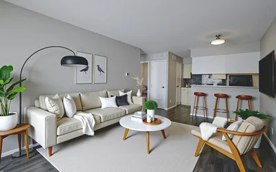 Contemporary open-concept living room with sleek design, featuring a cozy beige sofa, modern floor lamp, and stylish kitchen bar with stools.