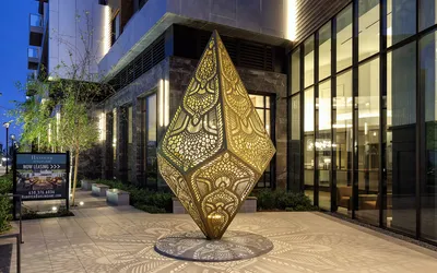 Modern apartment exterior at Hanover Burlingame with striking illuminated sculpture and elegant architecture at dusk.