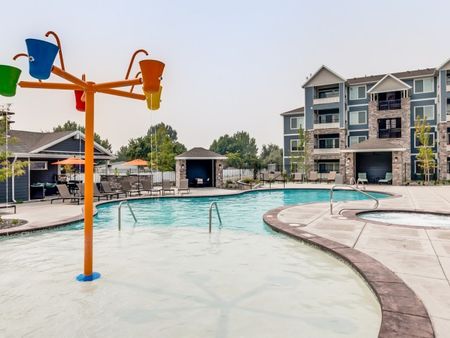Pool area with splash-pad and surrounding pool cabanas and tanning chairs