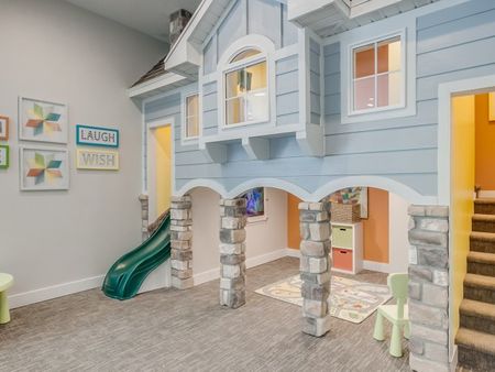 Indoor playroom with 2-level playhouse with slide and television